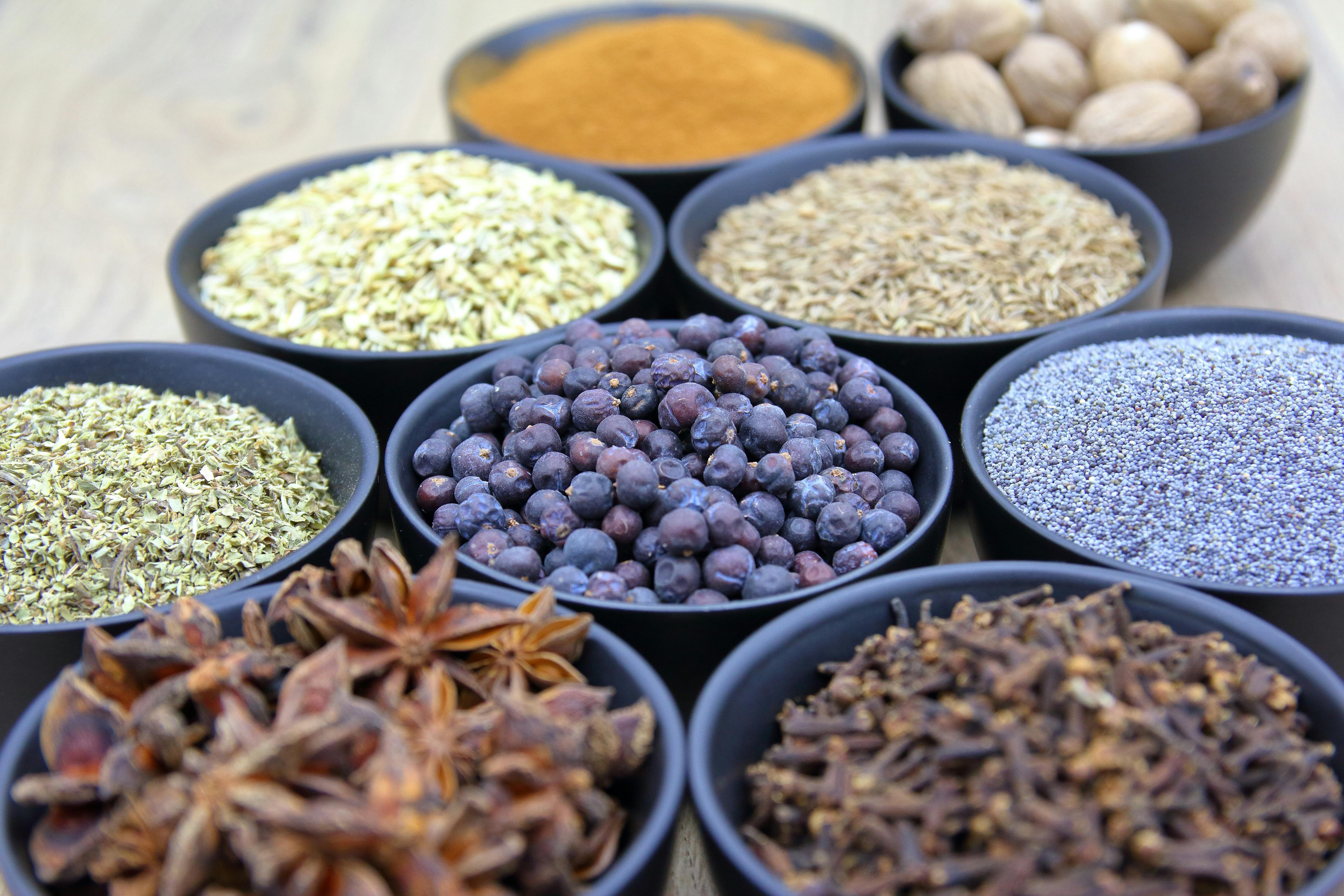 Several bowls of juniper berries and other spices on a tabel